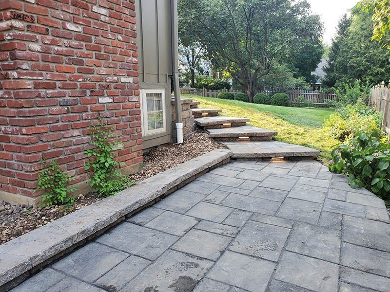 A stone walkway leading to a brick building with steps leading up to it.