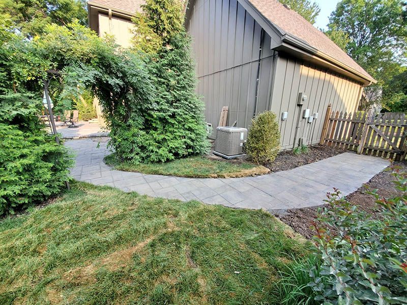 There is a walkway leading to a house in the backyard.