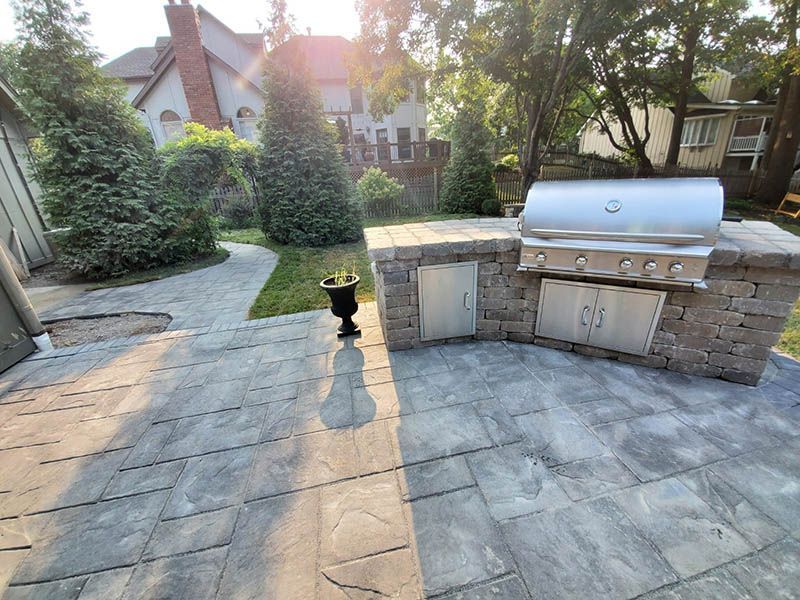 A grill is sitting on top of a patio in a backyard.
