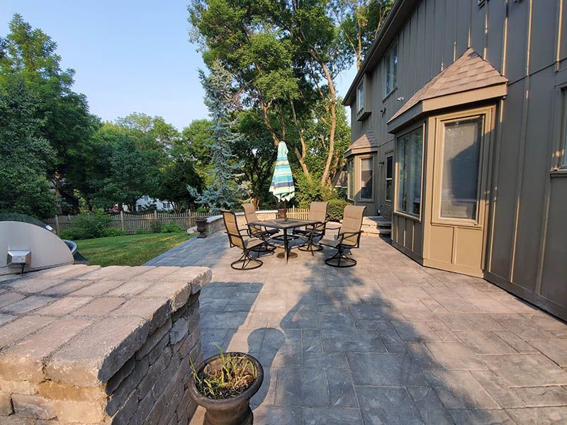 A patio with a table and chairs and an umbrella in front of a house.