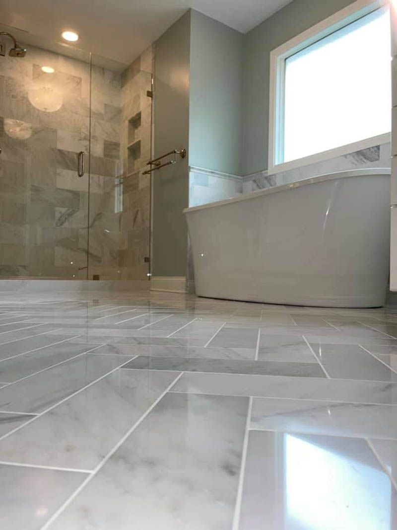 A bathroom with a tub , shower , and window.