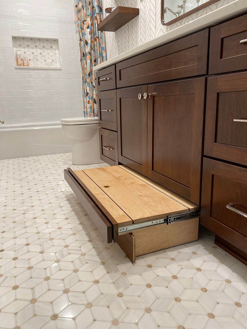 A bathroom with a sink , cabinets , and a wooden step.