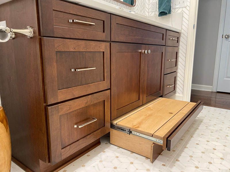 A bathroom vanity with drawers and a wooden step.