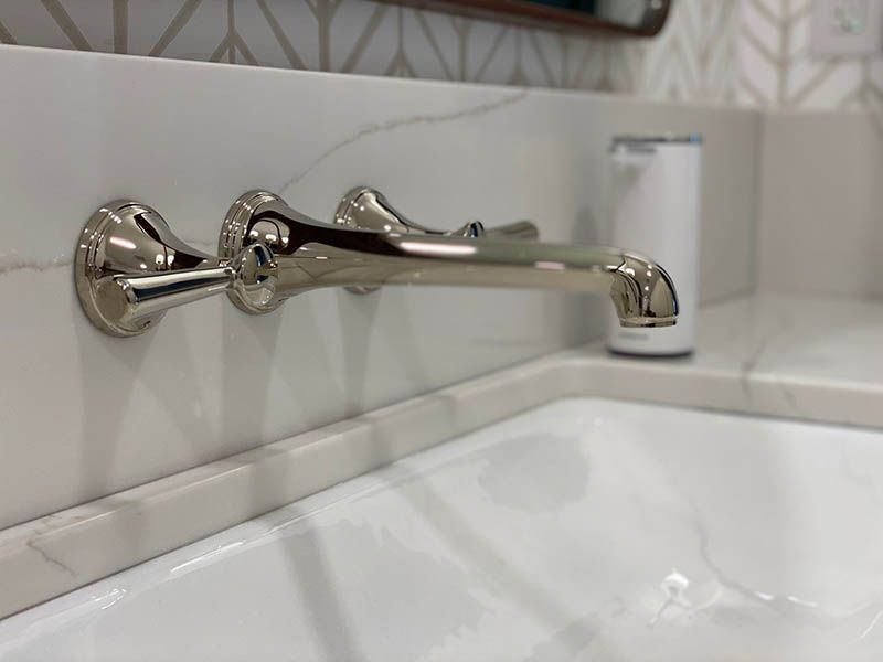 A close up of a bathroom sink with a faucet on the wall.