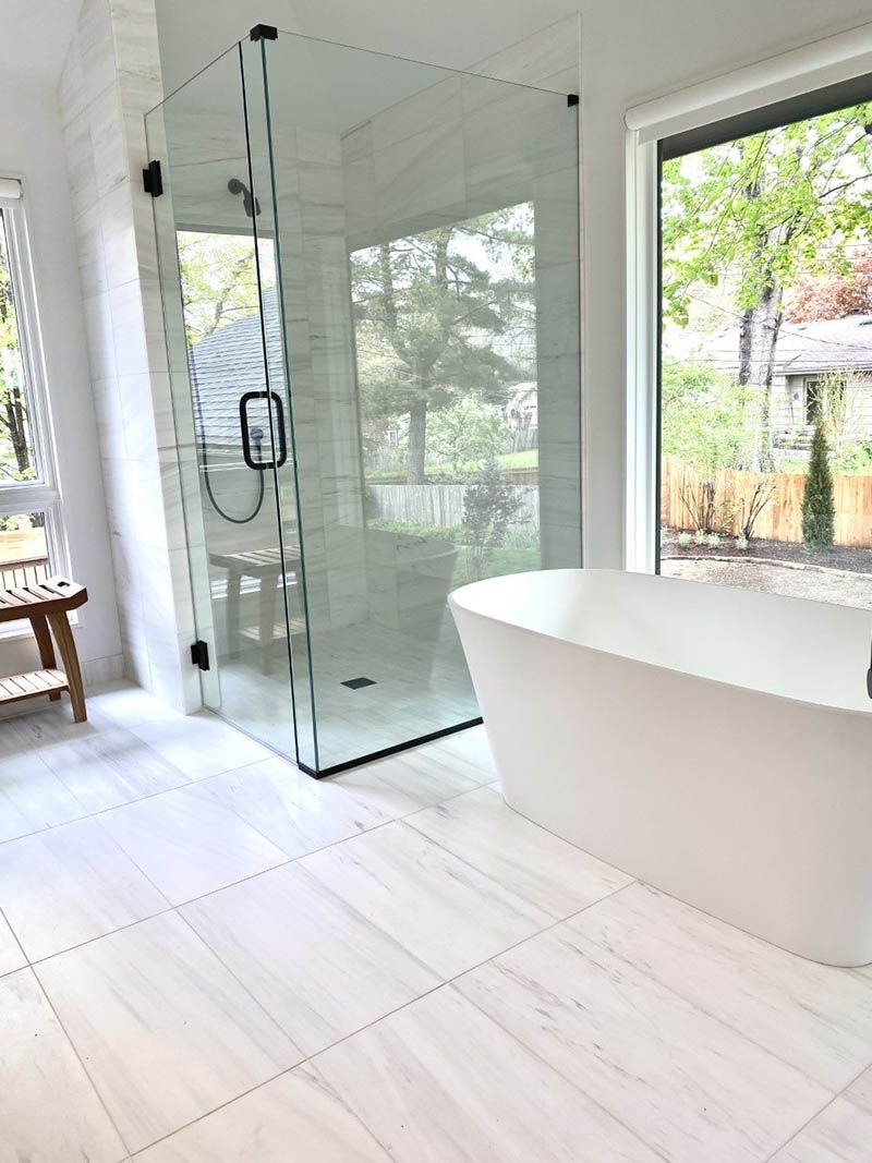 A bathroom with a tub , shower , and window.