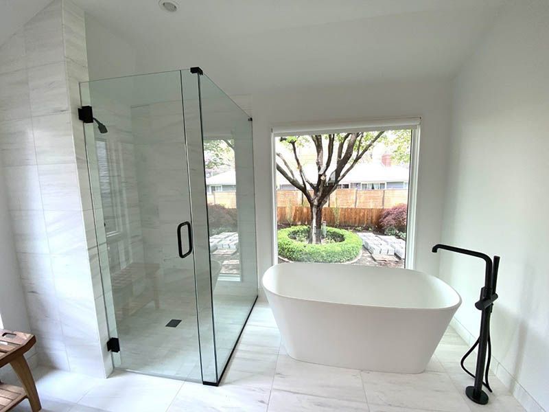 A bathroom with a tub , shower , and window.