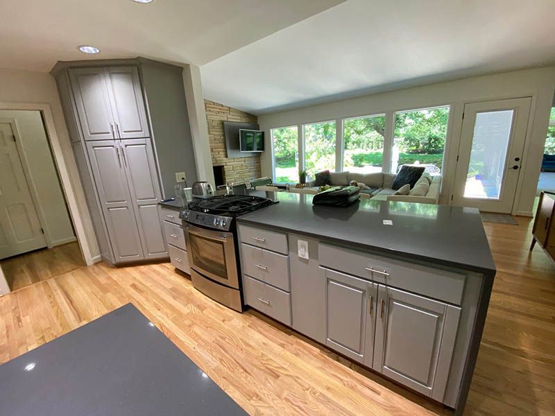 A kitchen with gray cabinets , a stove , and a large island.