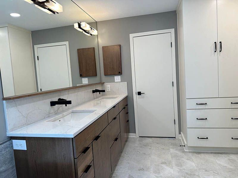 A bathroom with two sinks , a mirror and a closet.