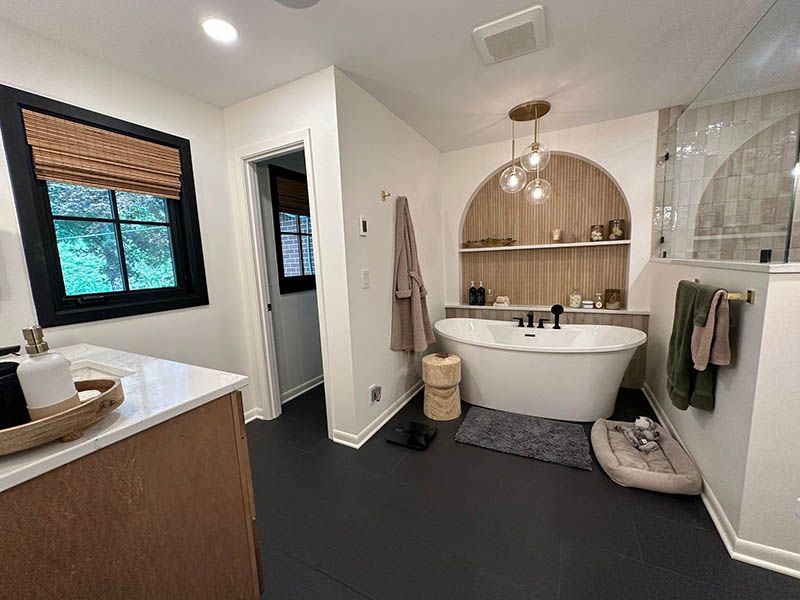 A bathroom with a tub , sink , and window.