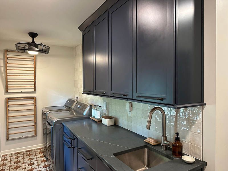 A laundry room with a sink , washer and dryer , and blue cabinets.