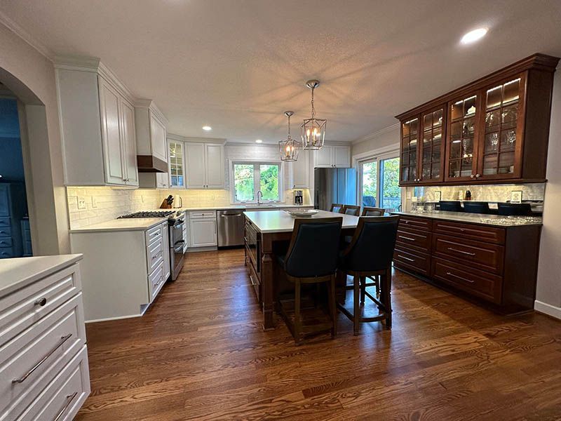 A kitchen with hardwood floors , white cabinets , stainless steel appliances , and a large island.