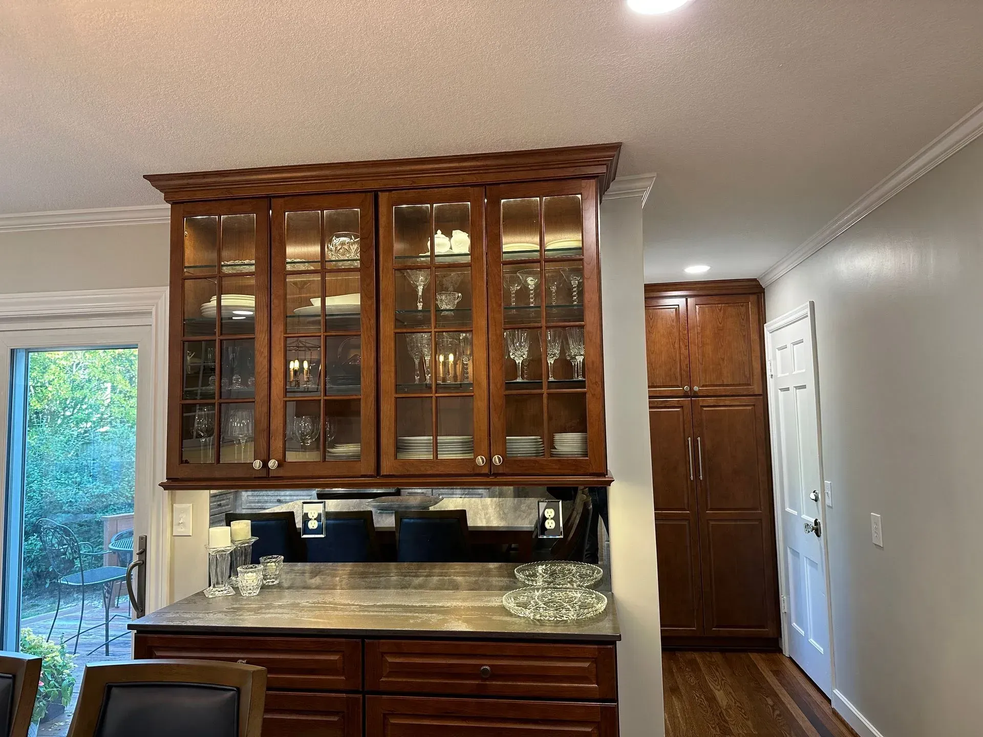 A kitchen with wooden cabinets and a glass door hutch.