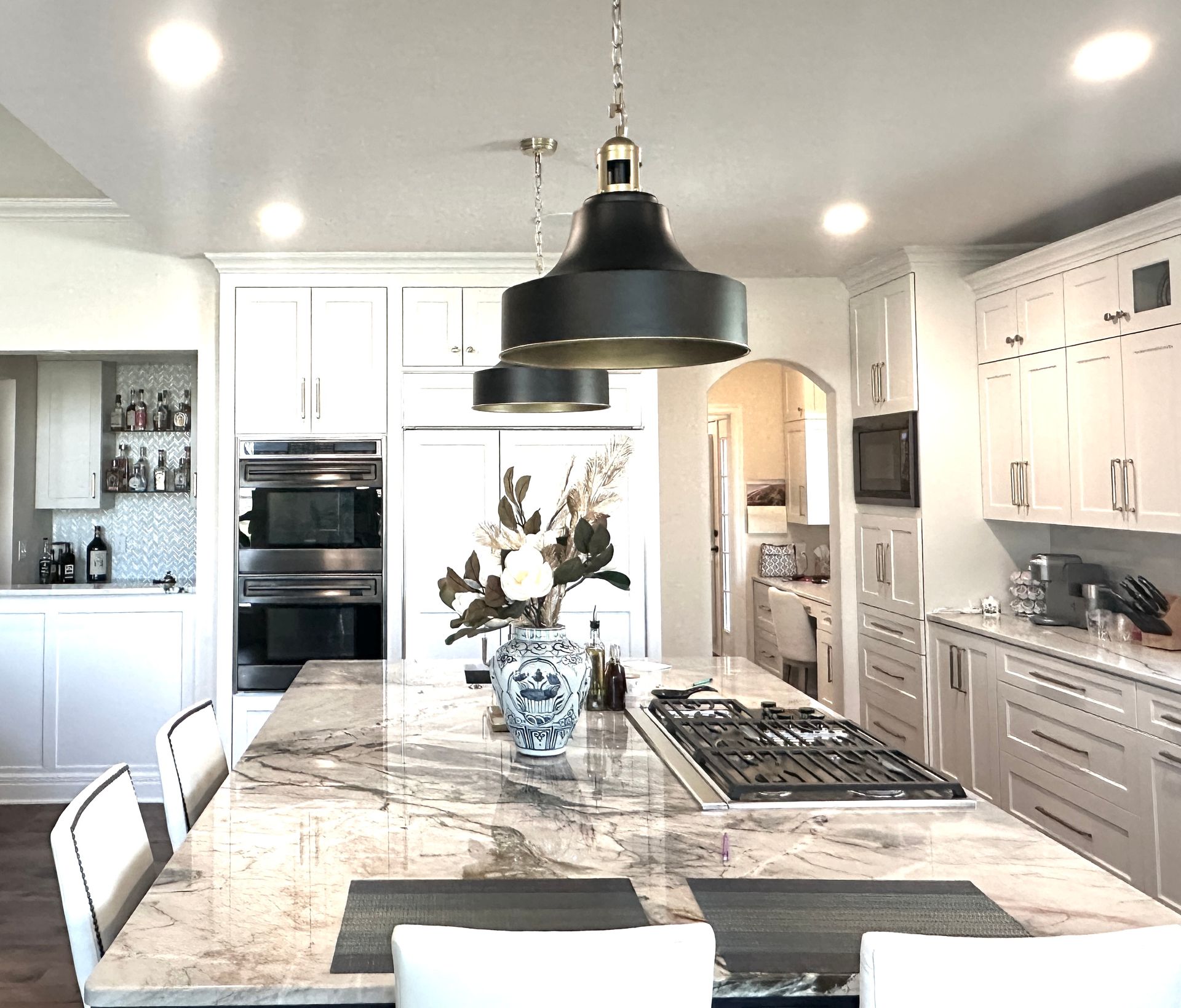 A kitchen with white cabinets and a large island in the middle