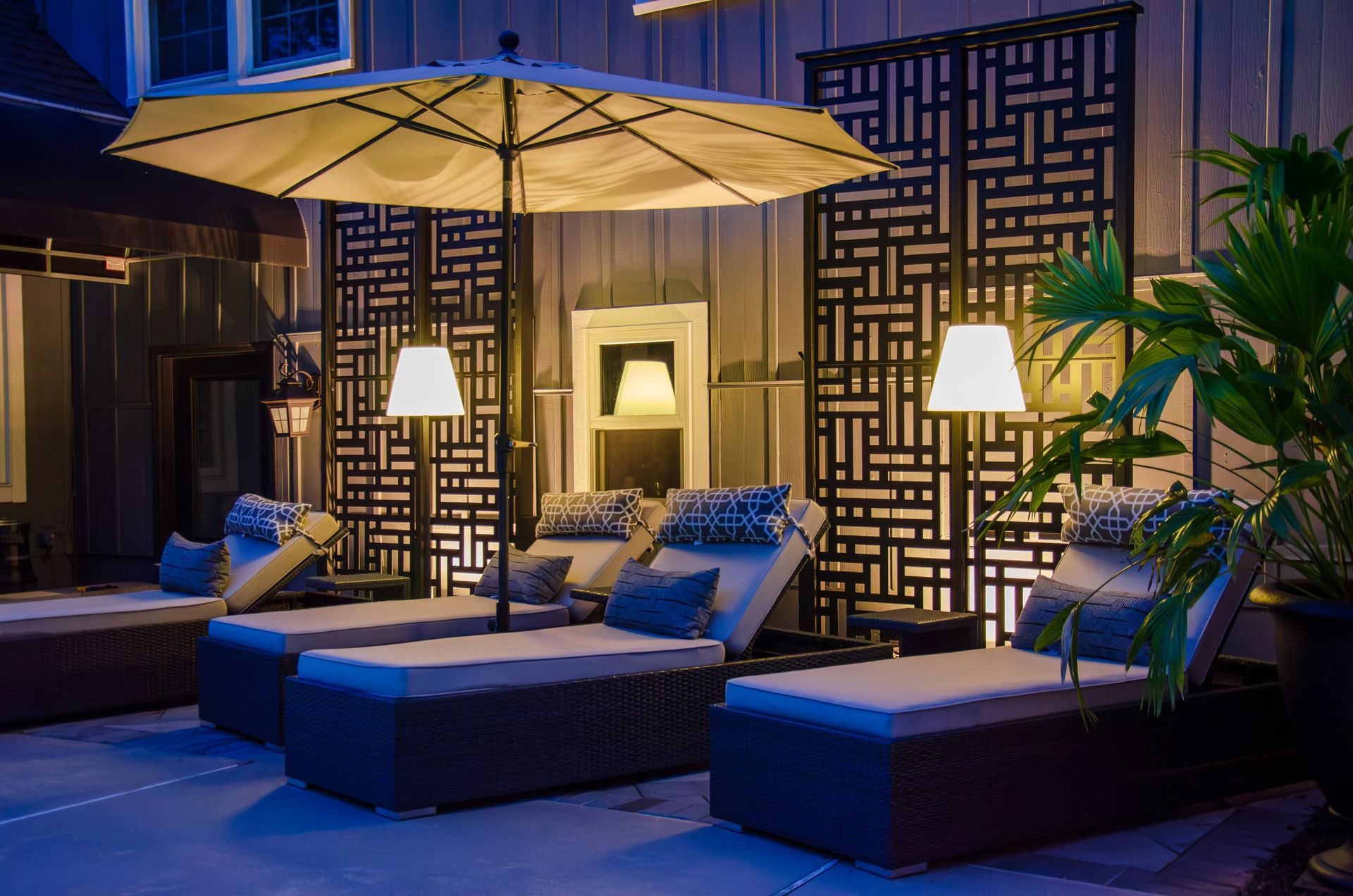 A patio with lounge chairs and umbrellas at night.
