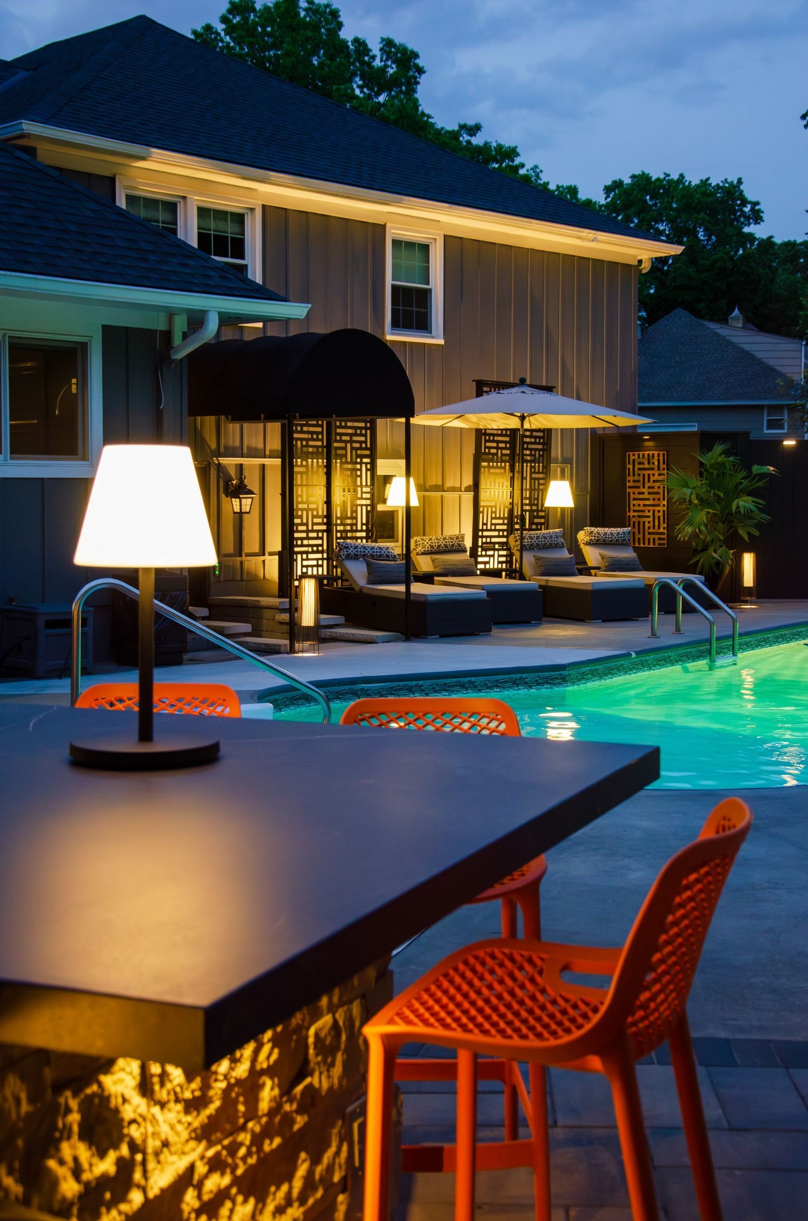 A table with a lamp on it in front of a swimming pool
