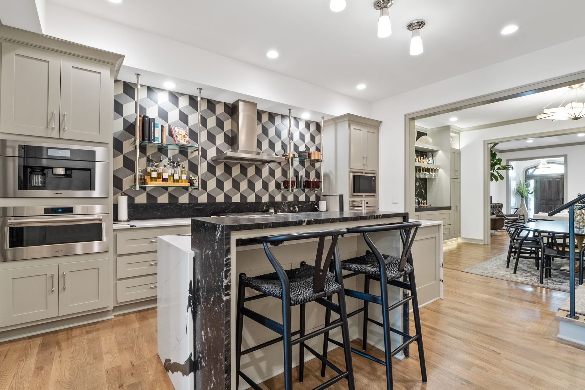 A kitchen with a large island and stools in it.