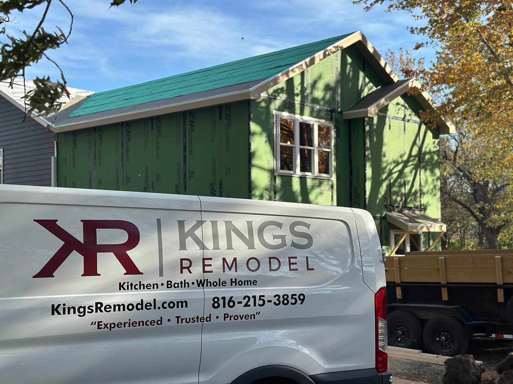 A kings remodel van is parked in front of a house under construction.