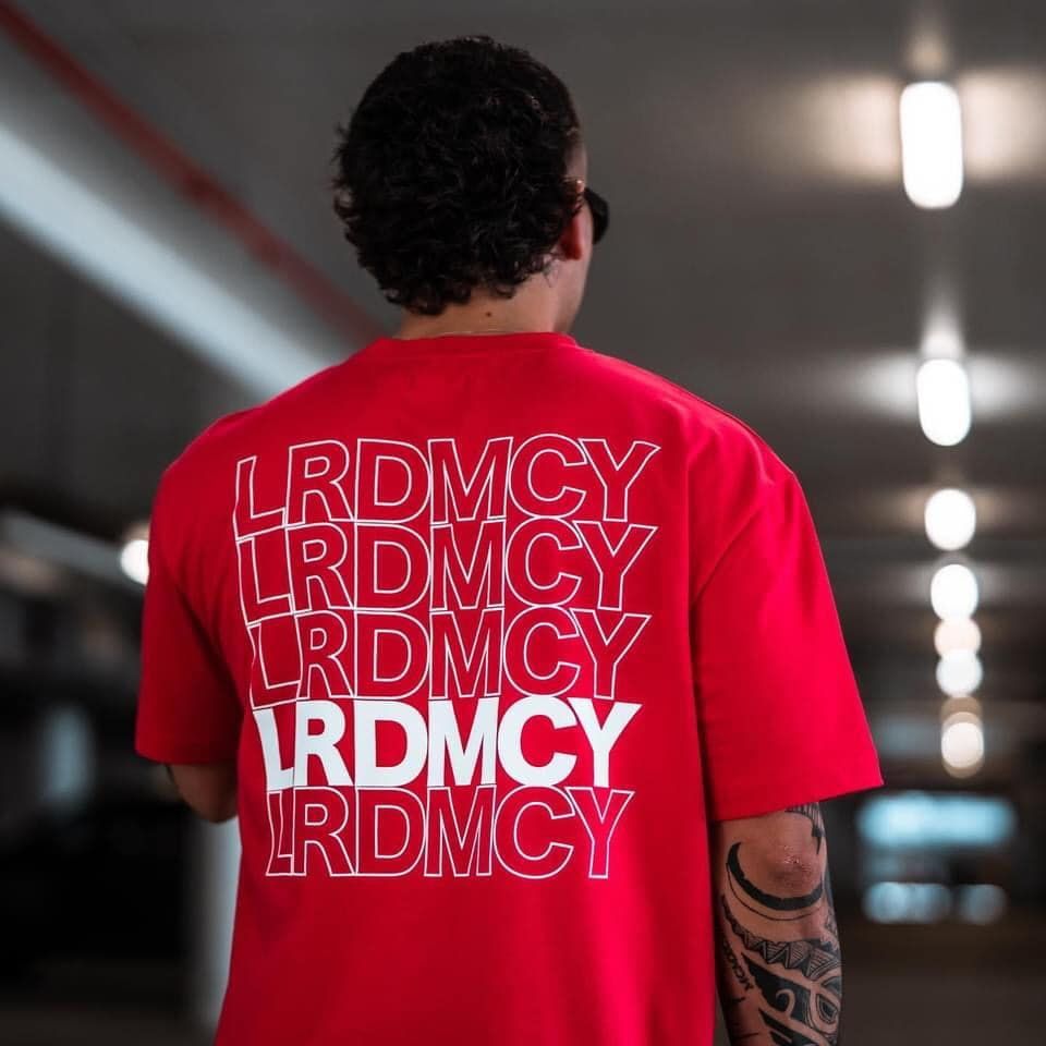 A Man Wearing A Red Shirt That Says Lrdmcy On The Back — Carnival Clothing In Miami, QLD