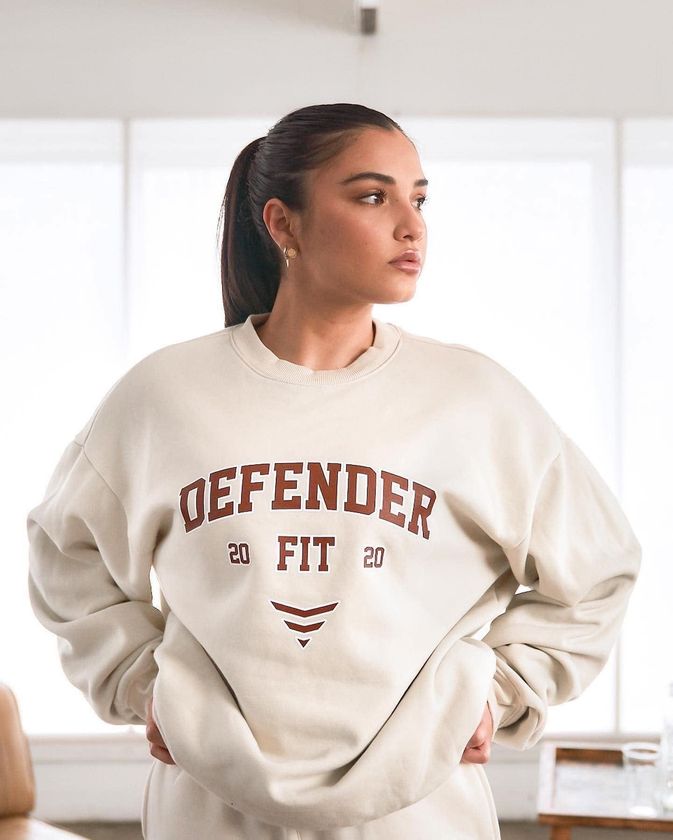 A Woman Is Wearing A White Sweatshirt With The Word Defender On It — Carnival Clothing In Miami, QLD
