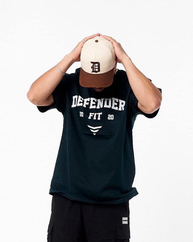 A Man Wearing A Defender T-shirt And A Hat Covering His Face — Carnival Clothing In Miami, QLD