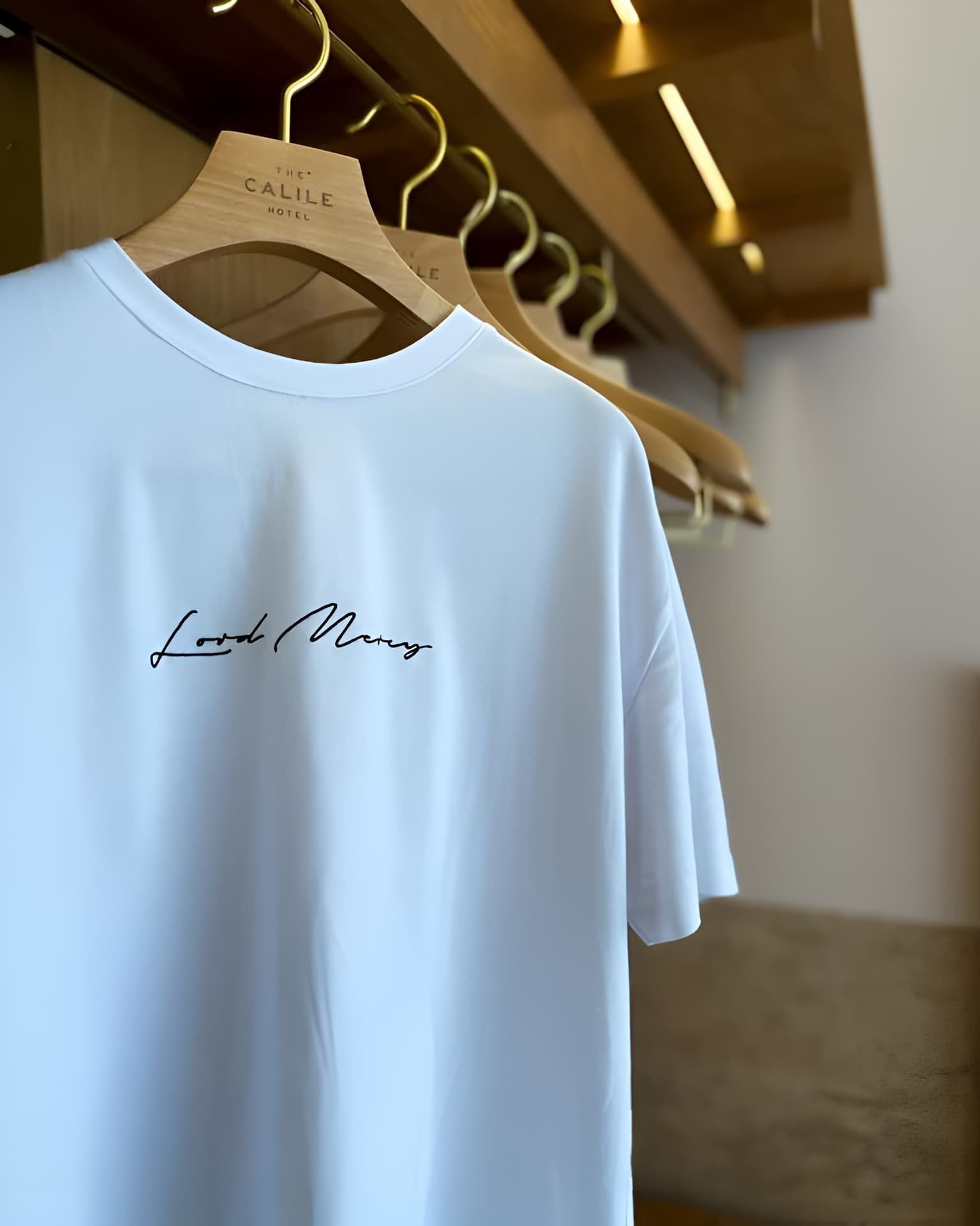 A White T-shirt Is Hanging On A Wooden Hanger — Carnival Clothing In Miami, QLD