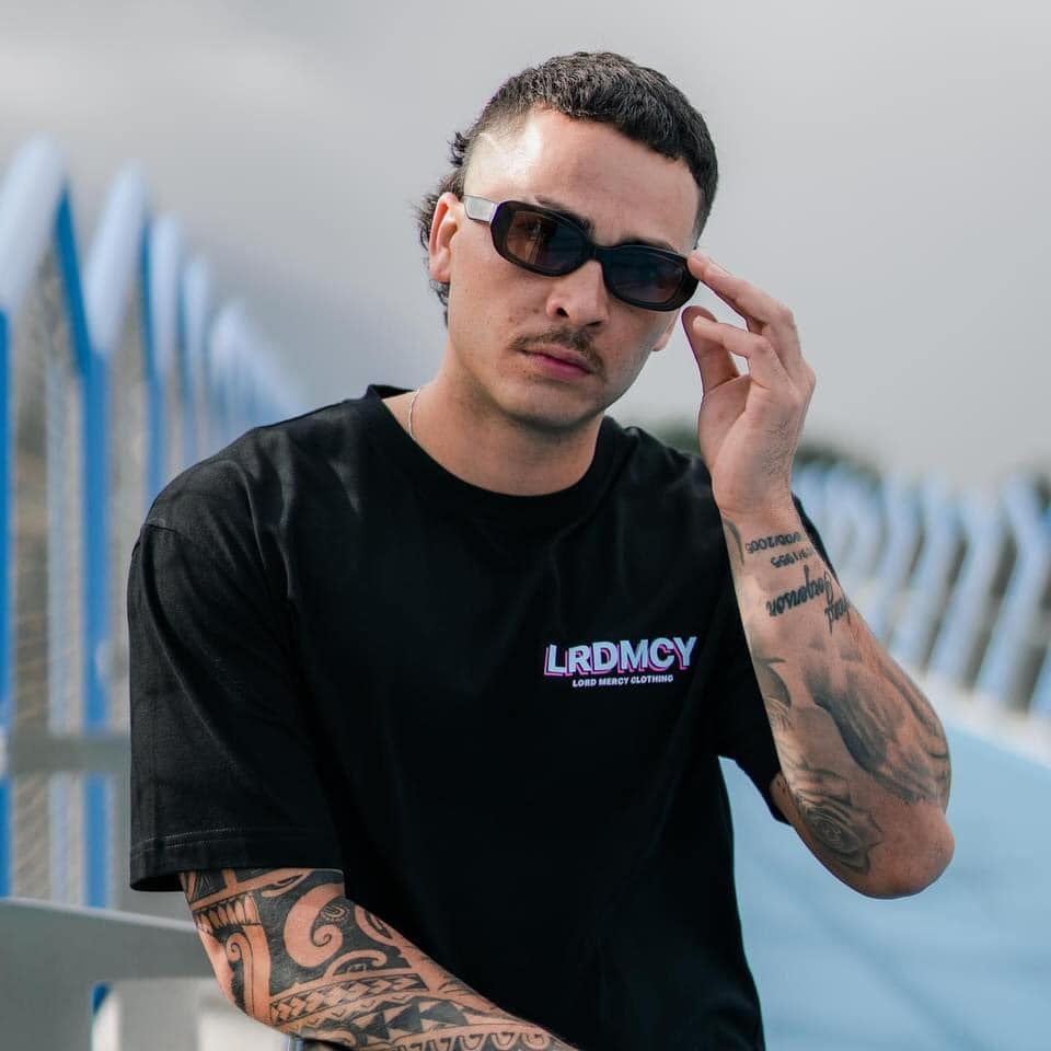 A Man Wearing Sunglasses And A Black Shirt That Says Lrdmcy — Carnival Clothing In Miami, QLD