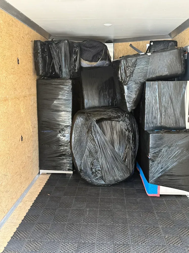 Trailer interior filled with black wrapped furniture and boxes.