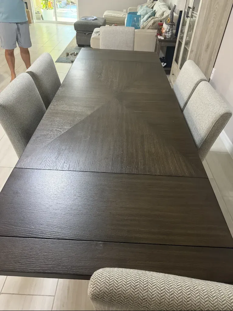 Long wooden dining table with six upholstered chairs.