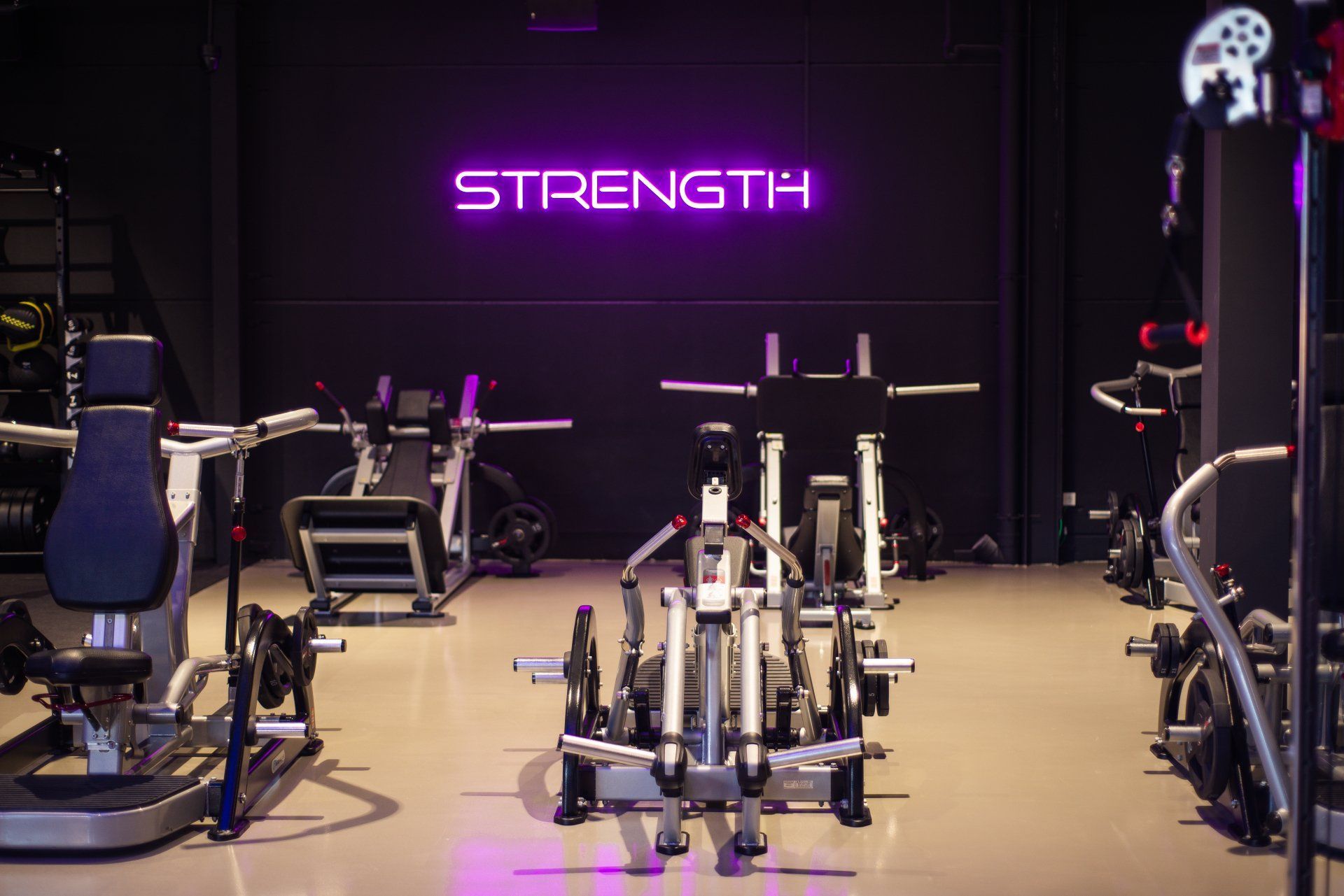 Gym interior with strength training equipment and a neon 