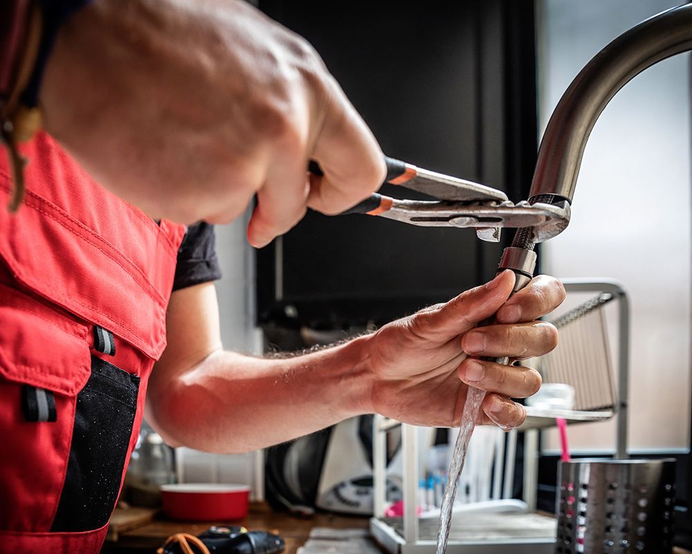 Plumbers in Ramona, CA performing a kitchen faucet repair with a wrench, ensuring smooth water flow.