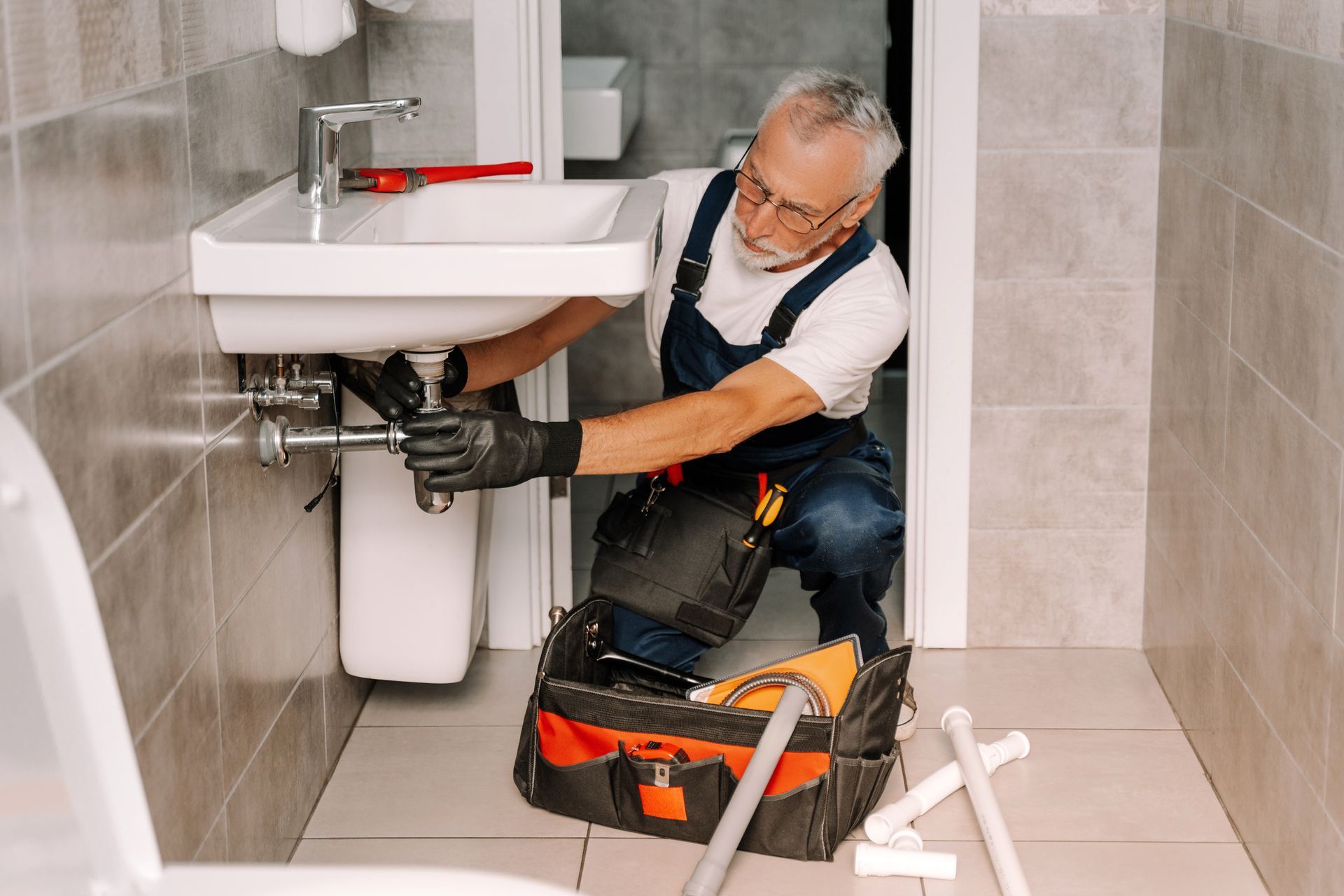 Plumbing contractors work on repairing a bathroom sink with expert tools and precision.