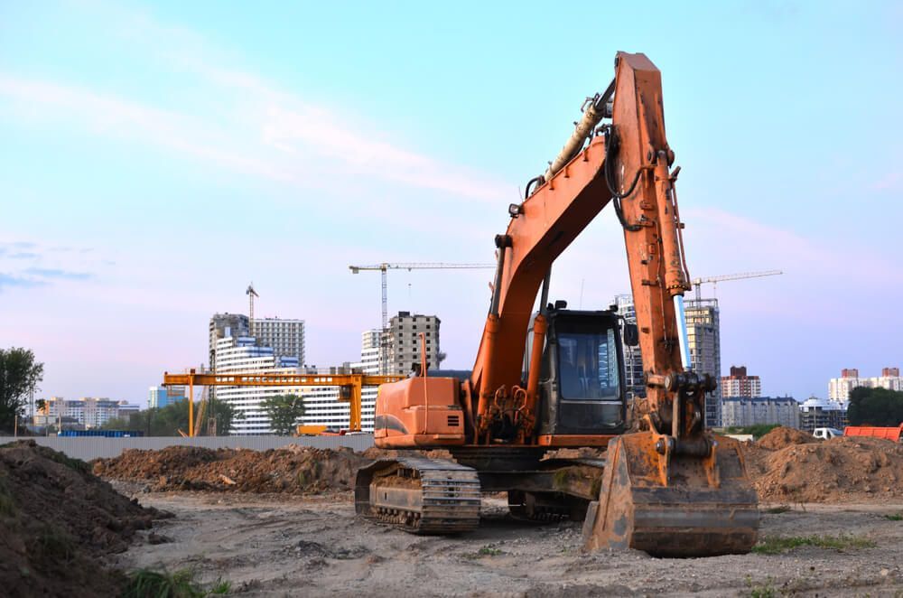 An Orange Excavator Is Parked On Top Of A Dirt Field At A Construction Site — Dicko's Bobcat & Tipper in East Bendigo, VIC