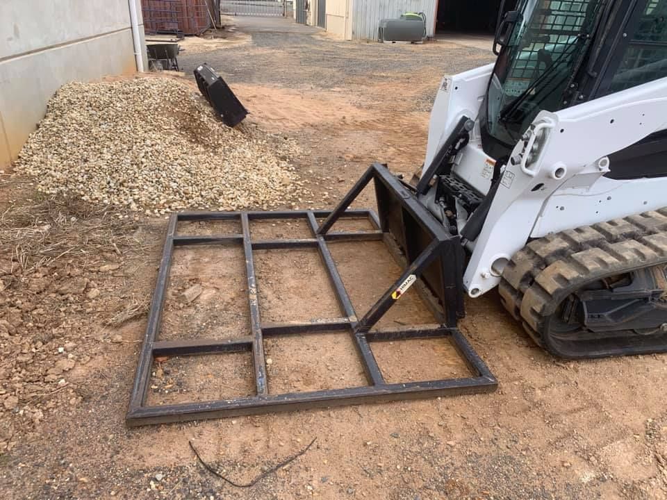 A Bobcat Is Parked In A Dirt Lot With A Metal Frame Attached To It — Dicko's Bobcat & Tipper in East Bendigo, VIC