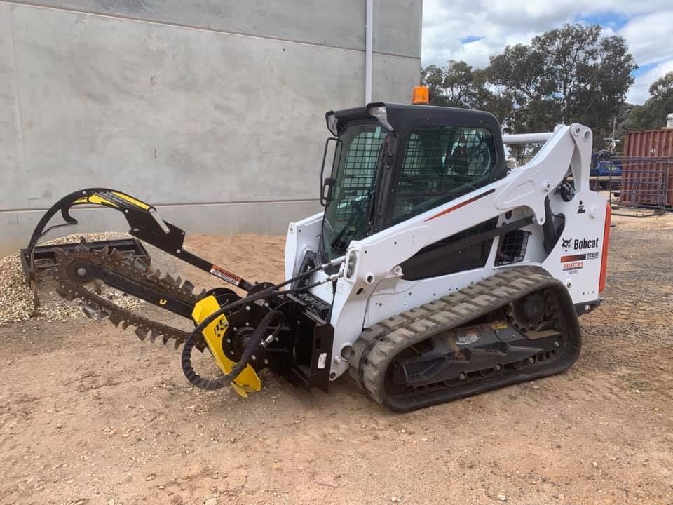 A Bobcat Tractor With A Trencher Attached To It Is Parked In A Dirt Lot — Dicko's Bobcat & Tipper in East Bendigo, VIC