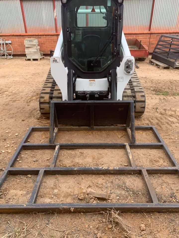 A Bobcat With A Metal Frame Attached And Placed On The Dirt Ground — Dicko's Bobcat & Tipper in East Bendigo, VIC