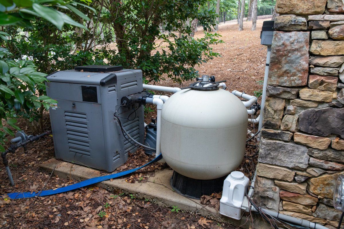 A pool filter and heater are sitting next to a stone wall.