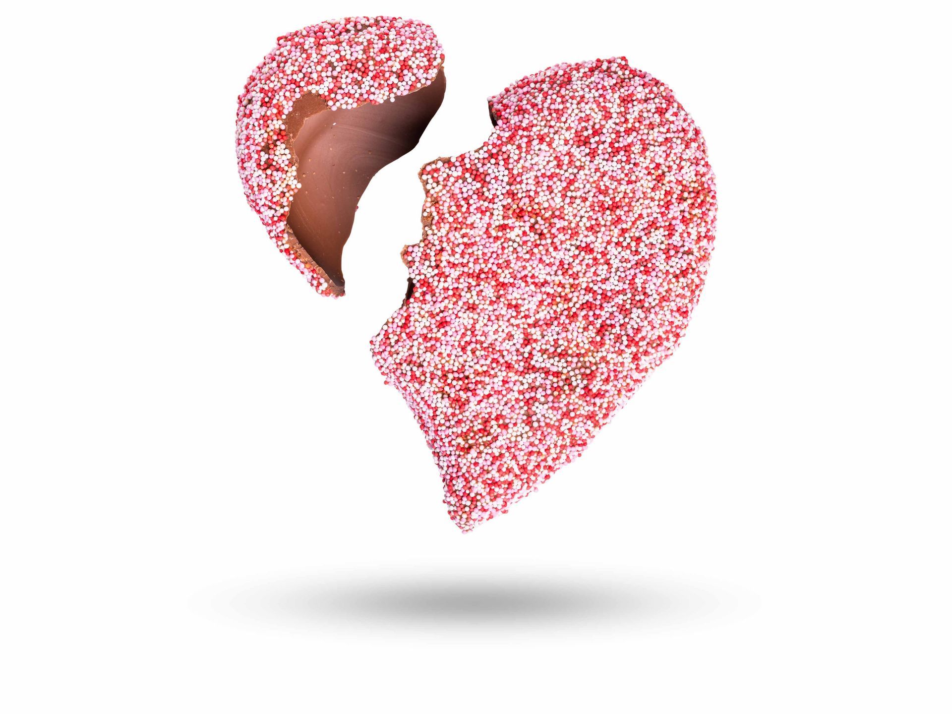 Gebroken hartjes bedekt met roze spikkels, waarvan één stukje is afgebroken en een schaduw werpt.