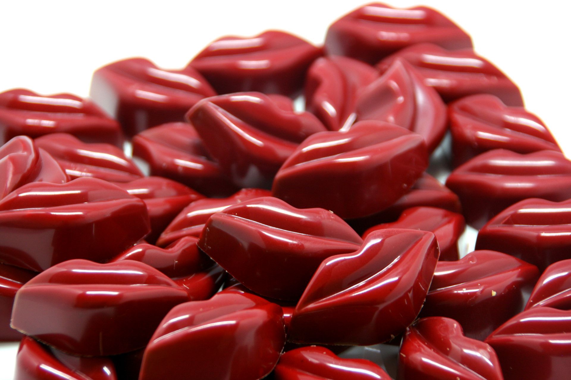 Stapel glimmende, rode, chocoladeachtige snoepjes in de vorm van lippen.