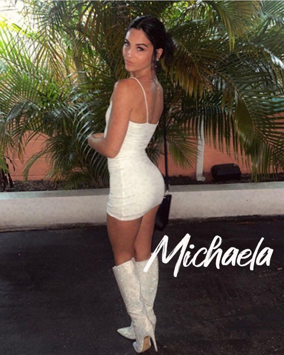 Woman in white dress and boots, posing outdoors; name