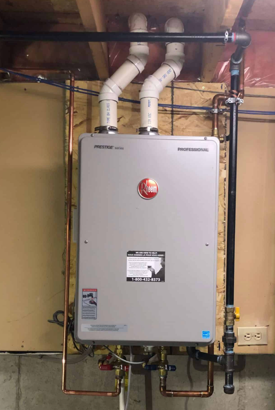 Wall-mounted tankless water heater with white vent pipes in a utility room