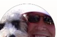 Person wearing sunglasses smiling beside a white dog in a round-cropped photo