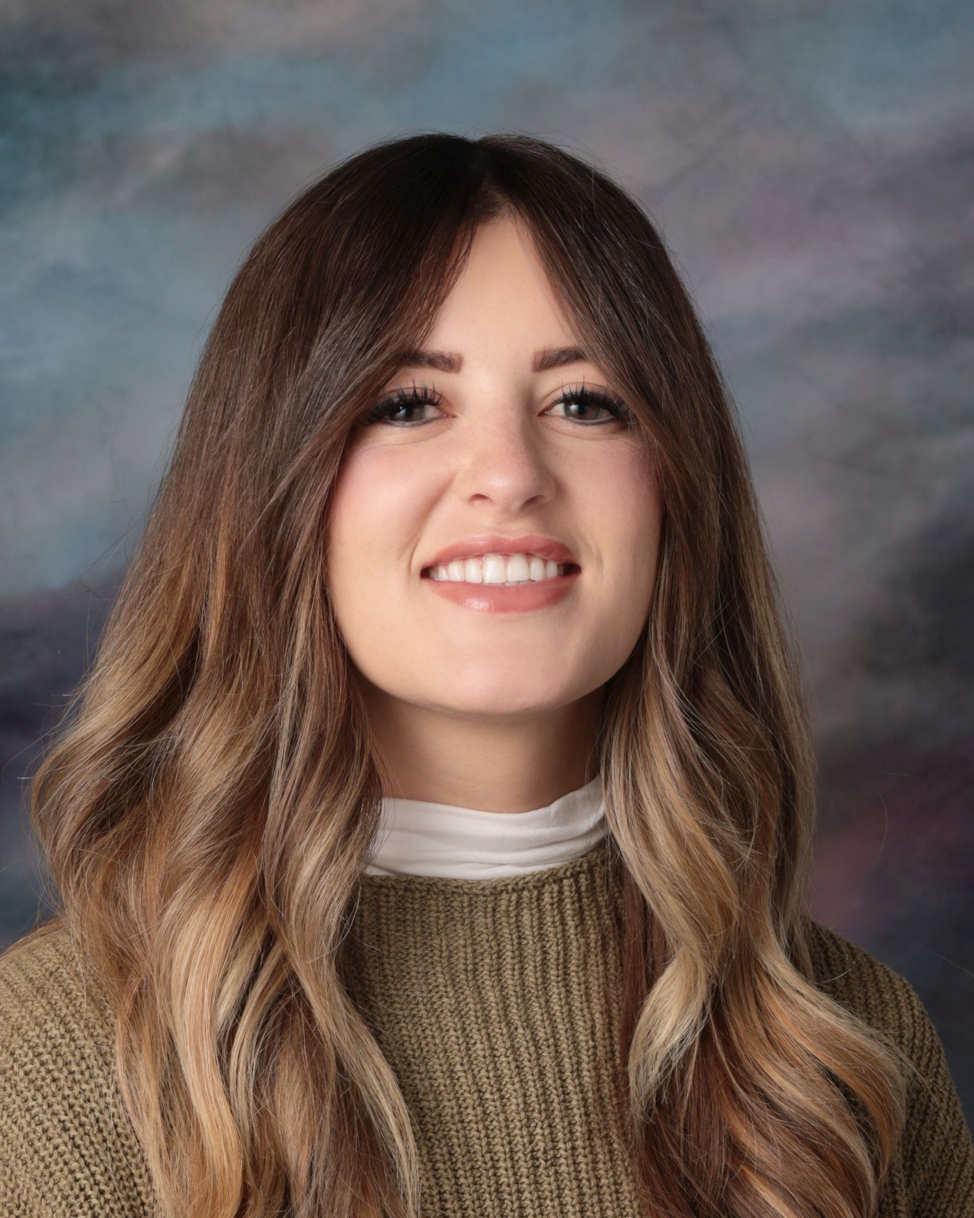The woman is wearing a pink jacket and smiling for the camera.