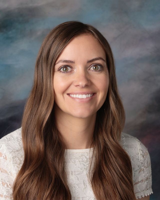 The woman is wearing a pink shirt and smiling for the camera.