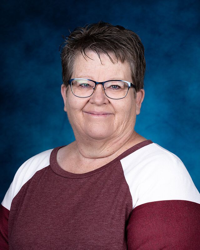 A woman wearing glasses and a red and white shirt is posing for a picture.
