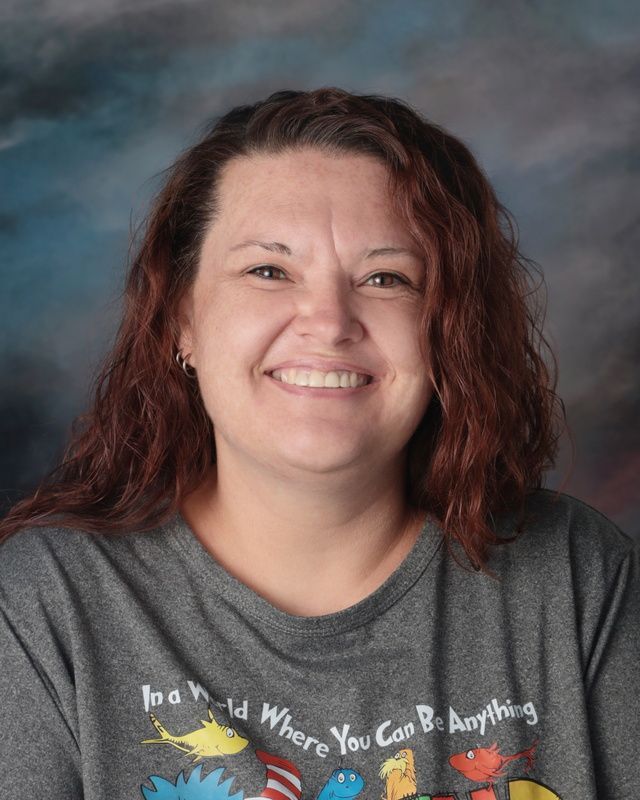 A woman wearing a black shirt with a rainbow on it is smiling for the camera.