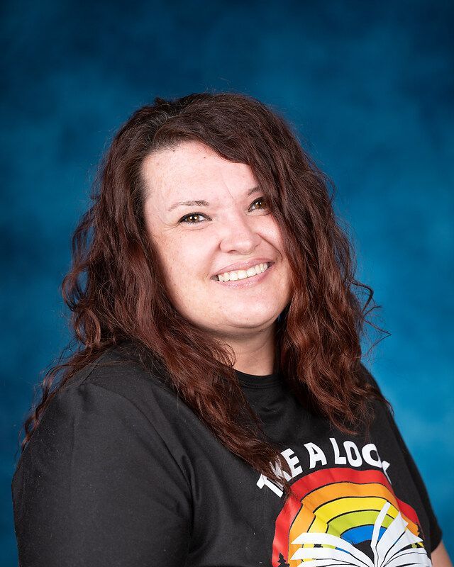 A woman wearing a black shirt with a rainbow on it is smiling for the camera.