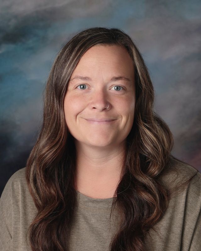 A woman is posing for a picture in front of a blue background.