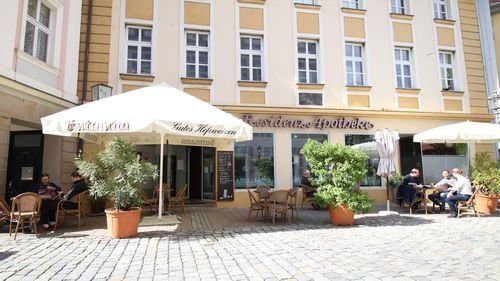 Alte Residenz Apotheke. Cafe Bar im Erdgeschoss eines  Historisches Gebäude, davor Sitzplätze im Freien.