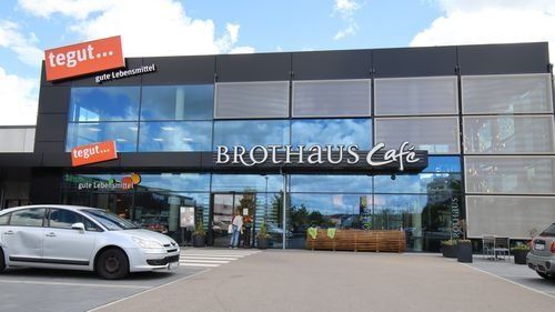 Brothaus Cafe neben tegut -Markt. Modernes Gebäude mit Glasfassade.