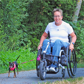 Frau im Rollstuhl mit kleinem Hund